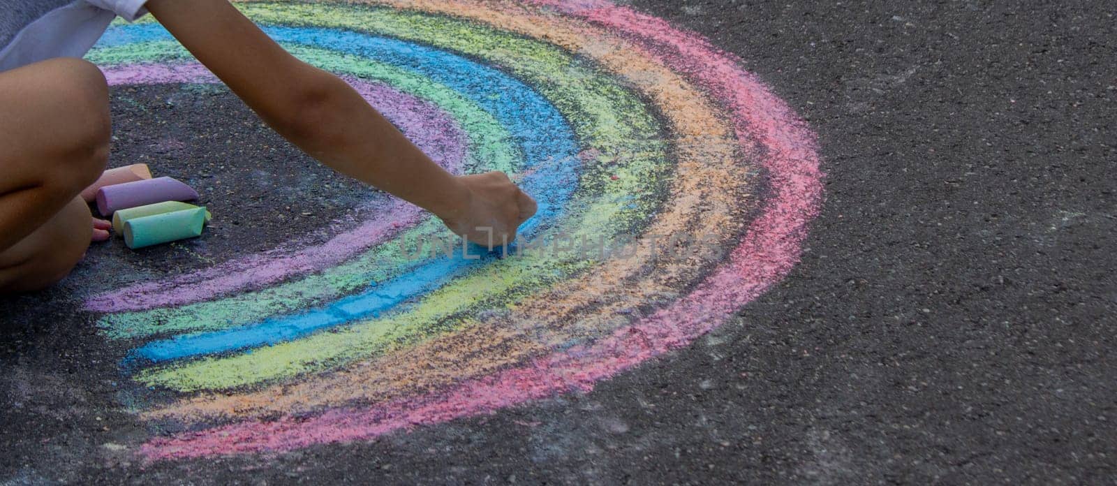 the boy draws with chalk on the asphalt. Selective focus.