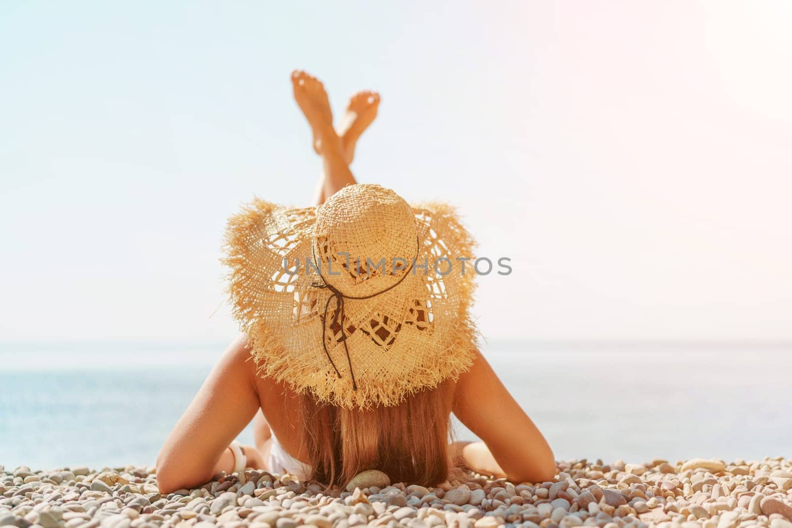 Beach Relaxation woman lies on a pebble beach, legs raised, and arms spread out. The concept of travel, vacation at sea.