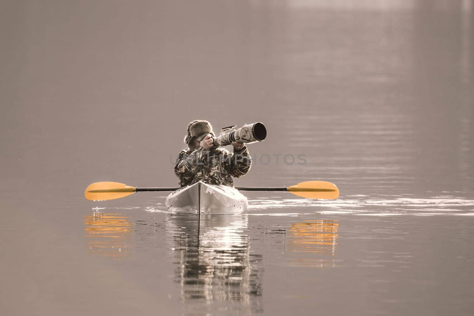 A photographer is out in his kayak taking pictures with his large camera and lens on the lake in Coeur d'Alene, Idaho.