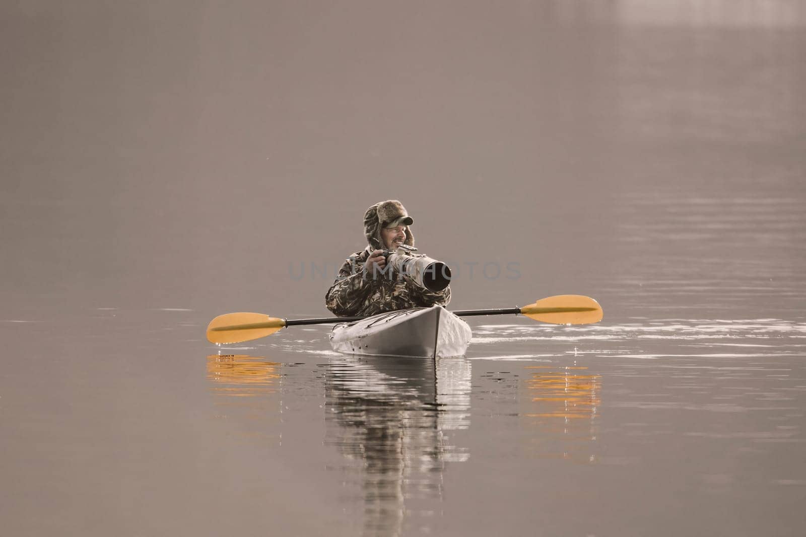 A photographer is out in his kayak taking pictures with his large camera and lens on the lake in Coeur d'Alene, Idaho.