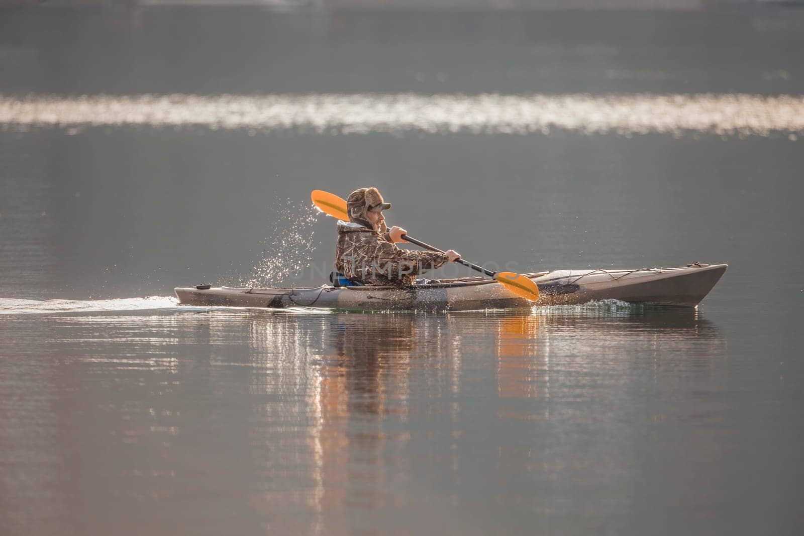 A man is paddling his kayak in chilly weather on Coeur d'Alene Lake in north Idaho.