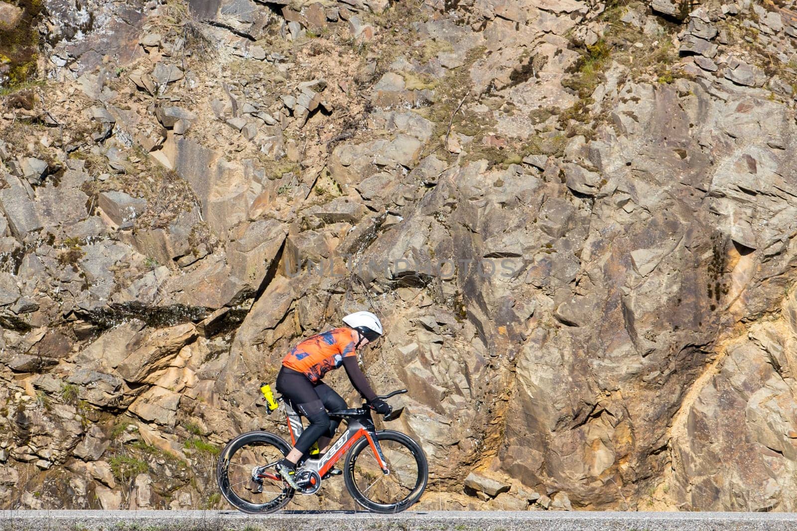 A man is riding a bike on a country road next to a rock wall in Coeur d'Alene, Idaho.
