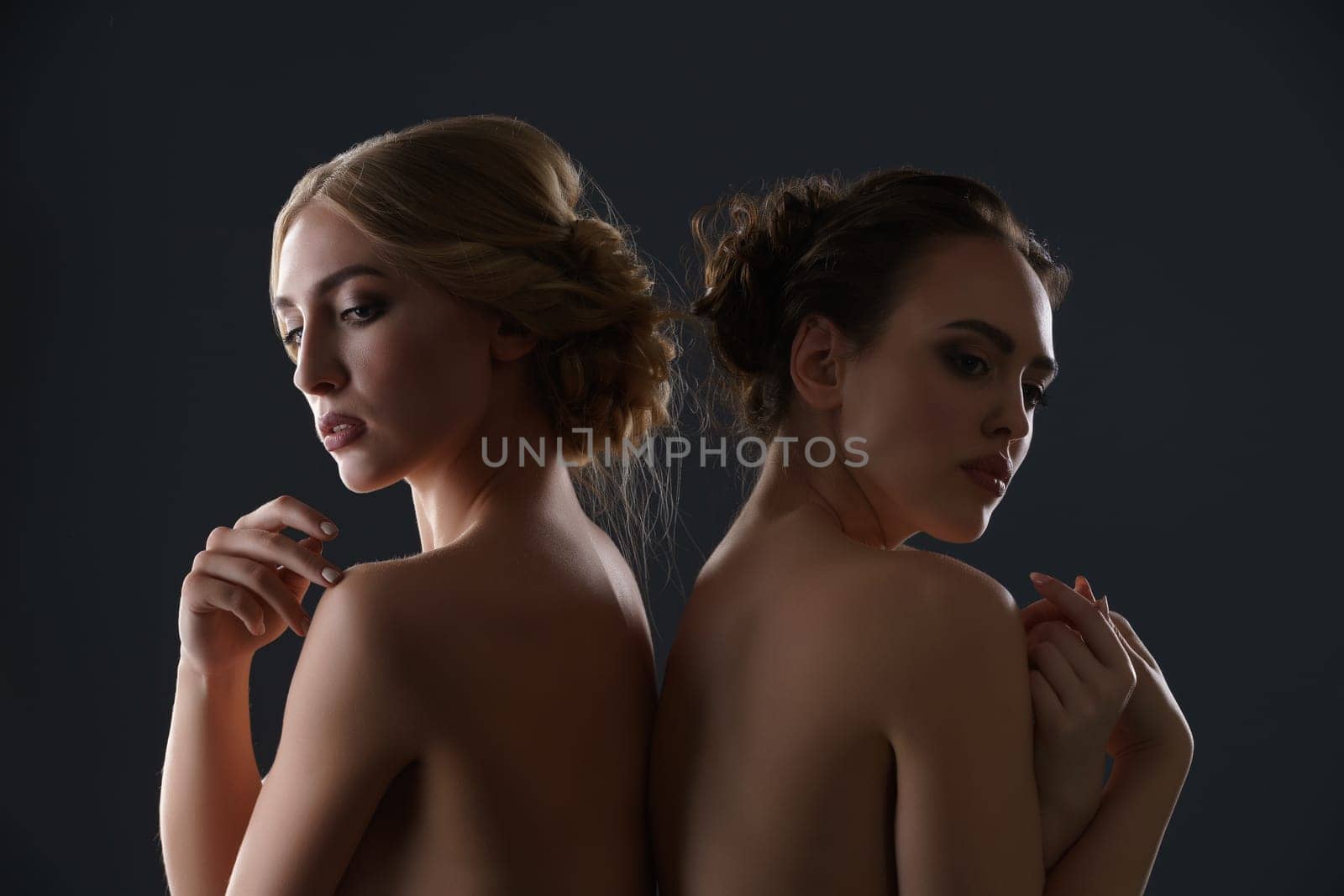 Two beautiful models with fine haistyles and make up posing together topless studio shot