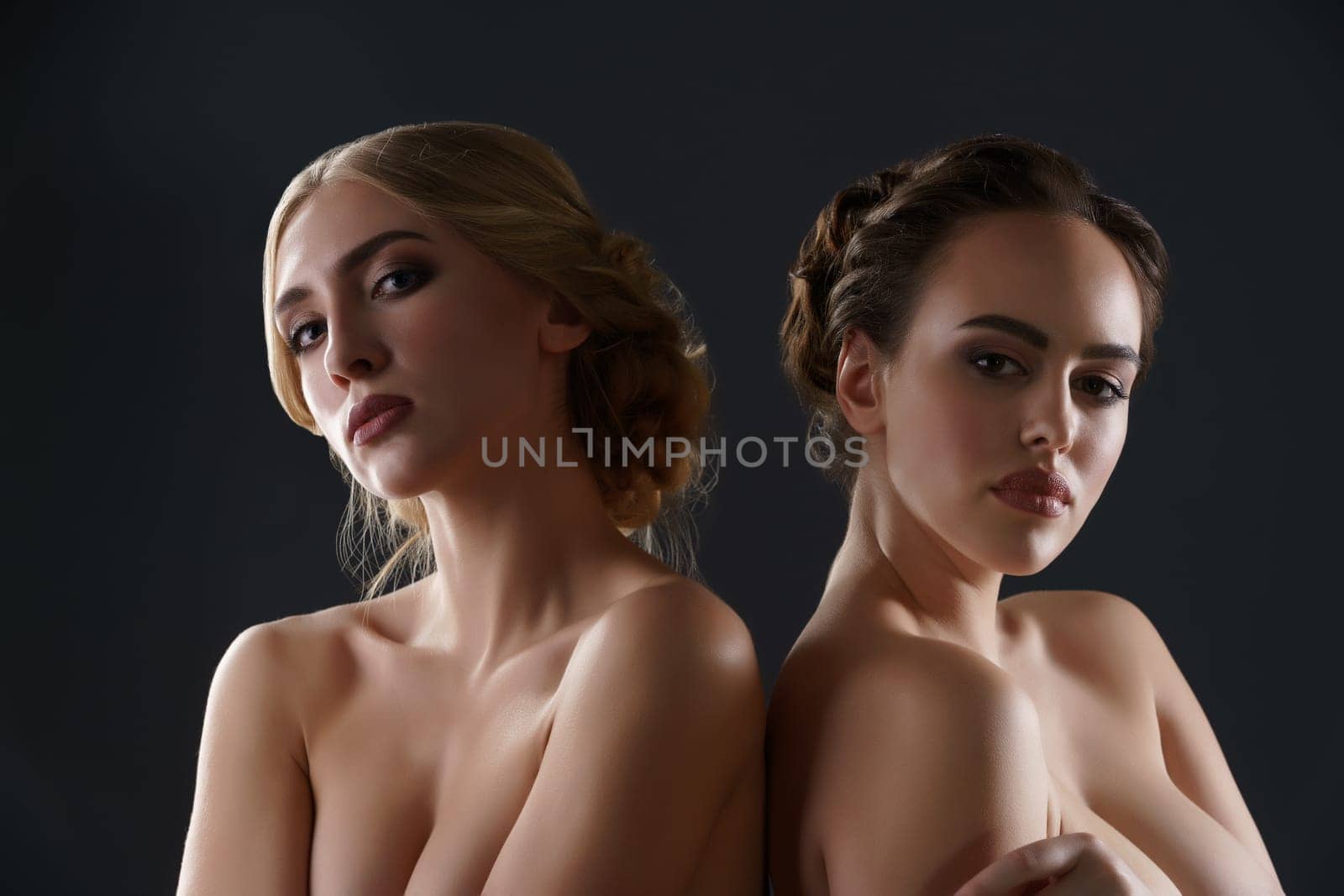 Two pretty women with beautiful hairstyle and makeup topless studio portrait
