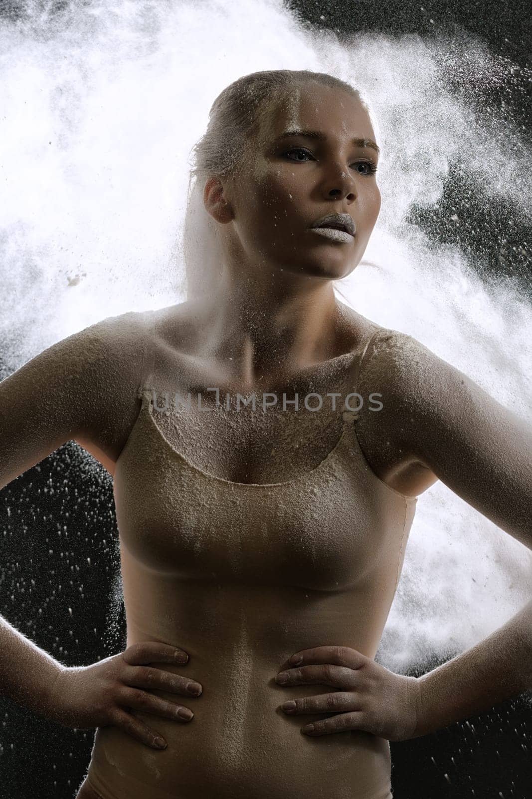 Young slim girl posing in white dust cloud artistic studio portrait
