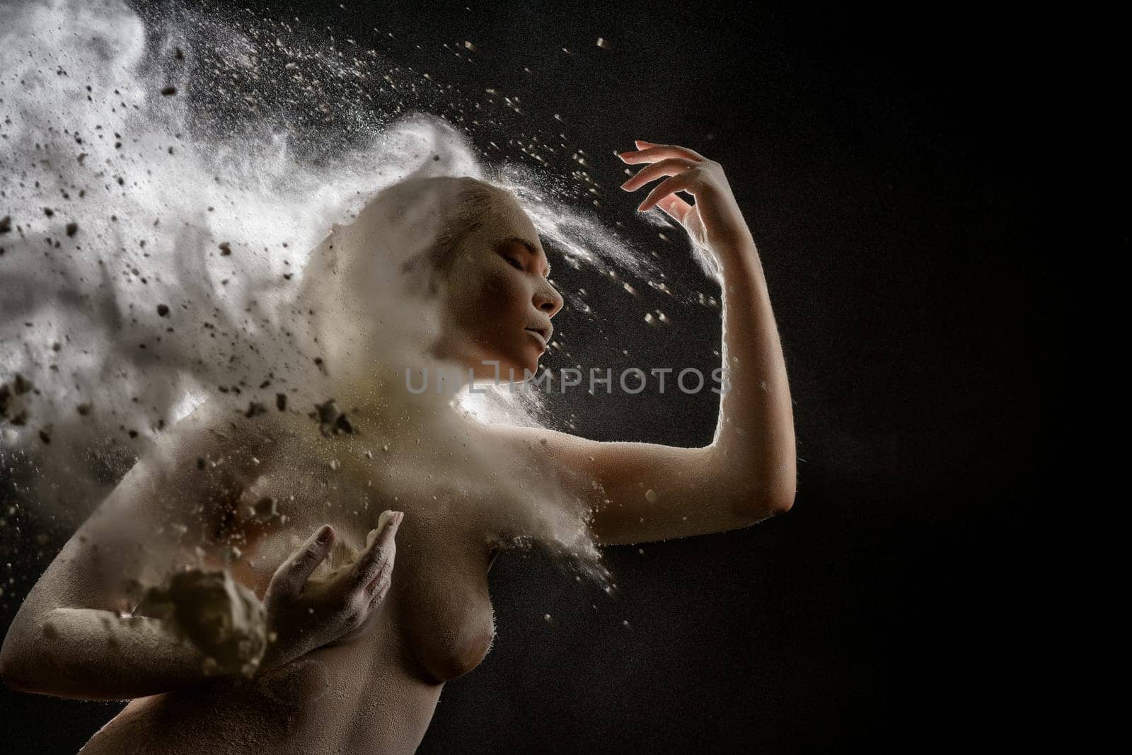 Young model topless in a cloud of white dust studio shot