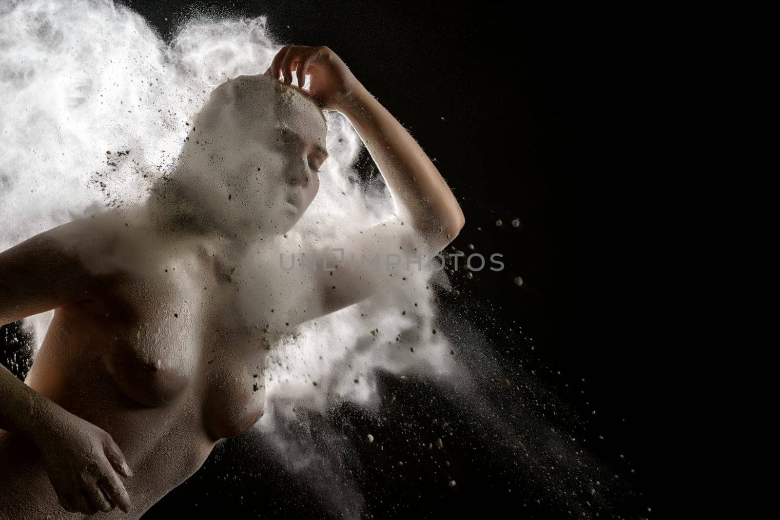 Young model topless in a cloud of white dust studio shot
