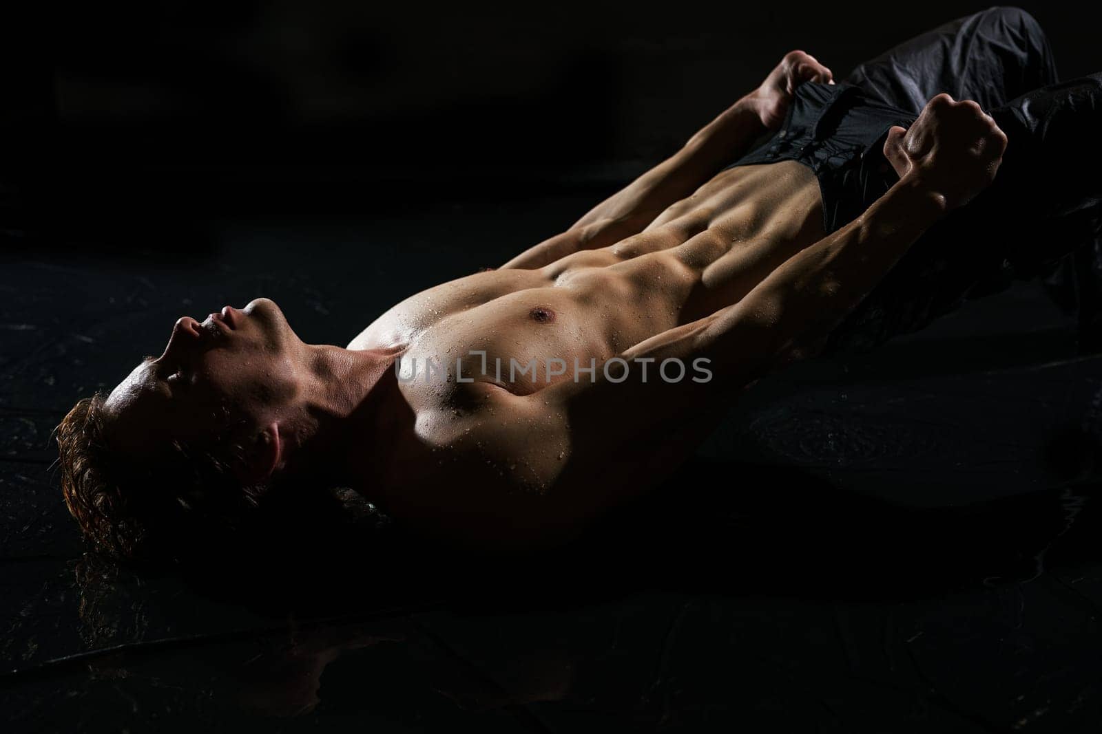 Athletic young man in jeans and with naked torso taking shower studio portrait