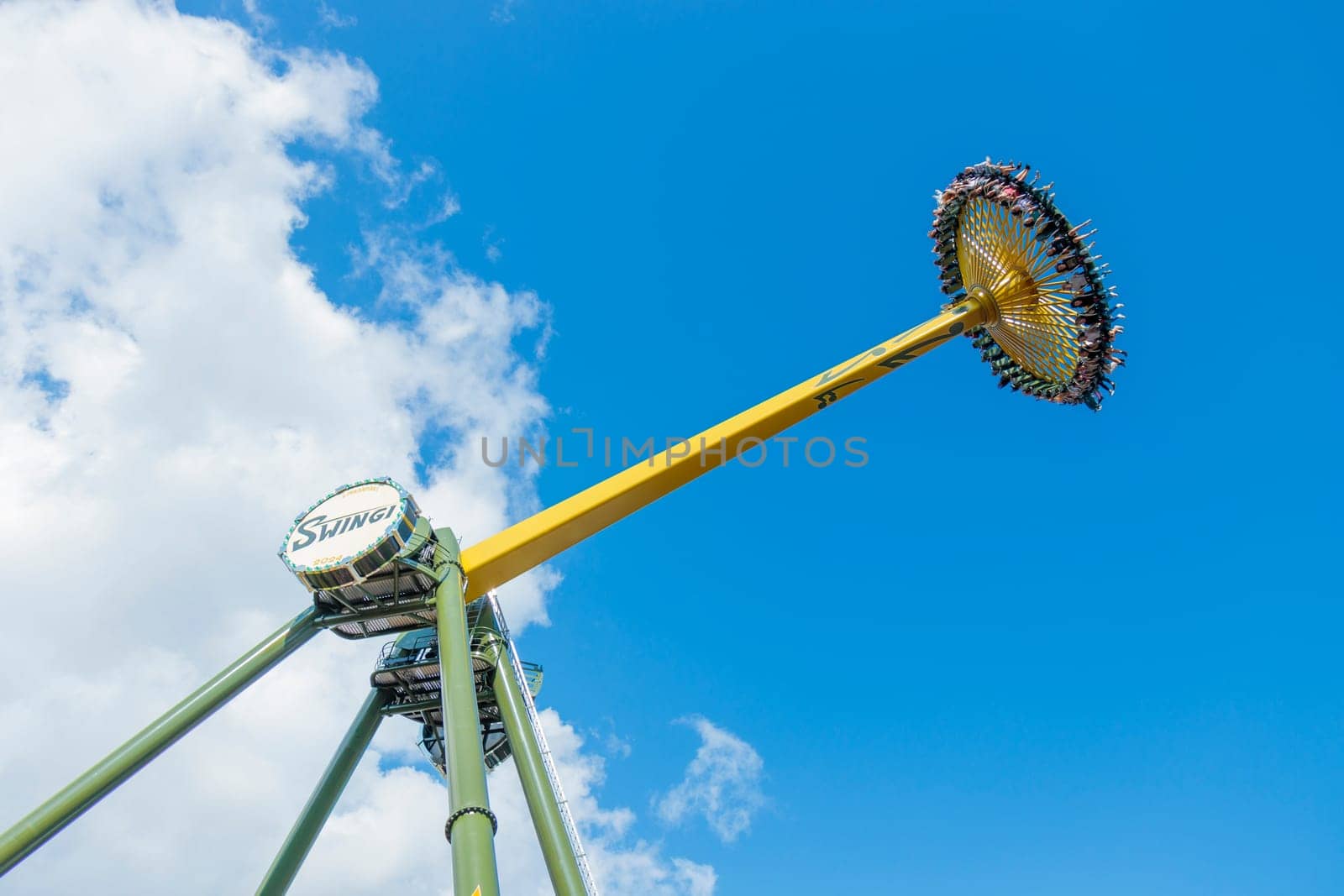 Helsinki, Finland - 19 July 2024: Linnanmaki Amusement Park, new roller coaster Swingi in motion, blue sky on a background, happy people