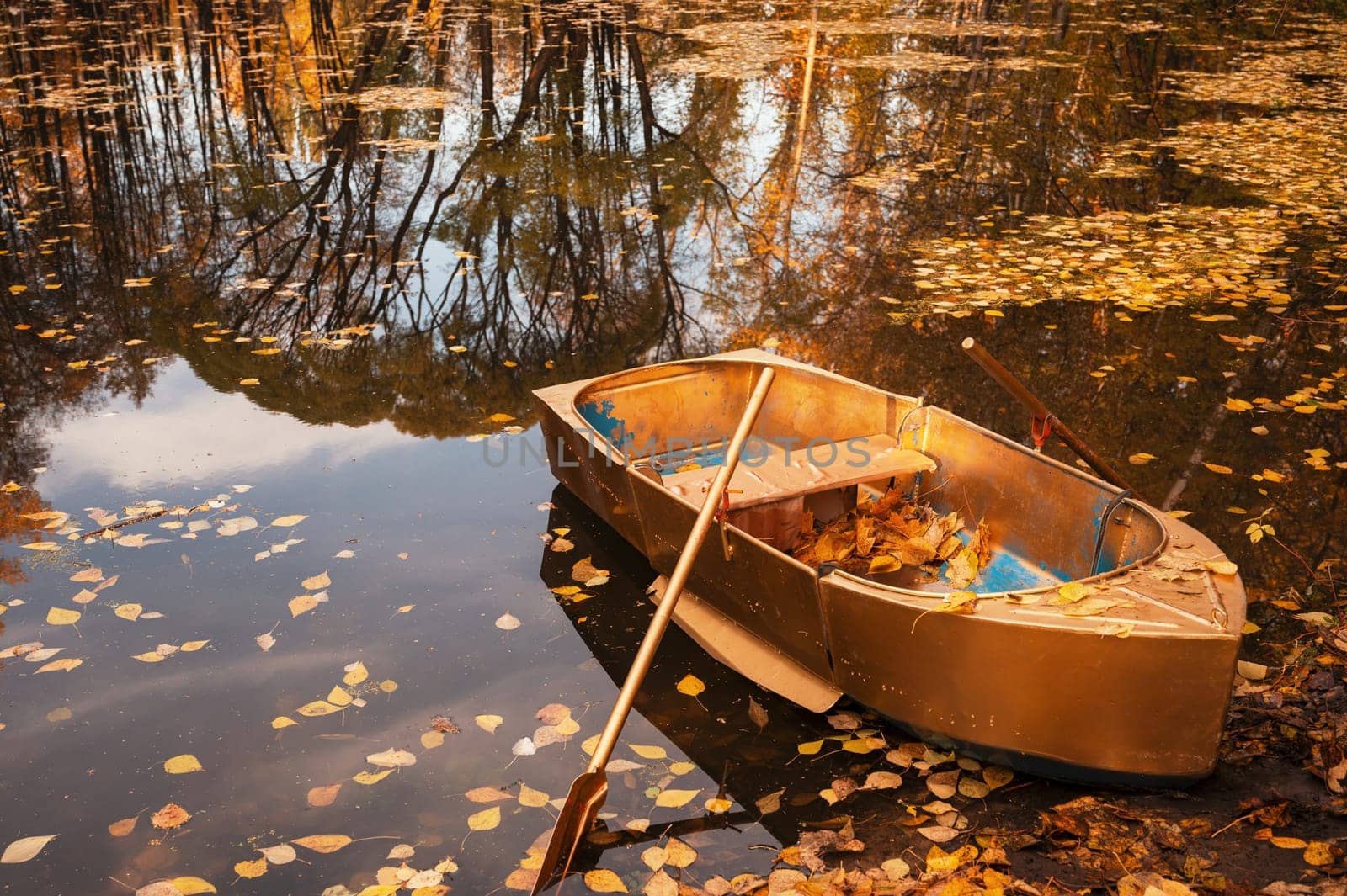Golden wooden boat at beautiful autumn sunny day. Autumn peaceful landscape. with reflections