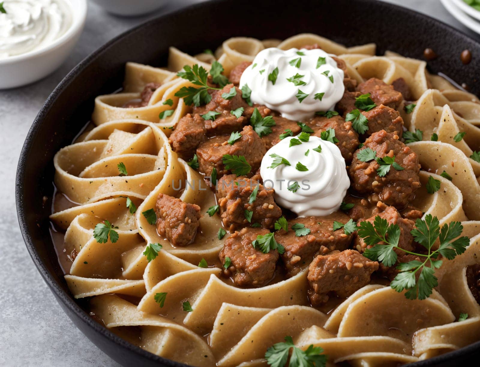 A steaming bowl of beef stroganoff features tender chunks of meat simmered in a rich, savory sauce, perfectly layered over egg noodles. It is garnished with fresh parsley and dollops of sour cream, creating a mouthwatering dish ideal for a cozy meal at home.