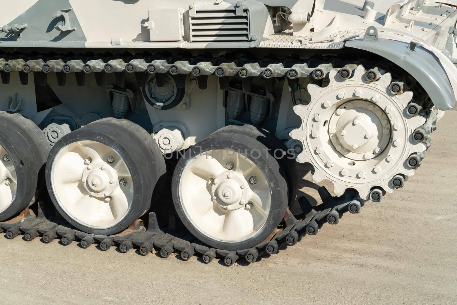 A military vehicle displays its tracks and wheels on sandy desert terrain. The machine showcases a rugged design crucial for navigating challenging environments.