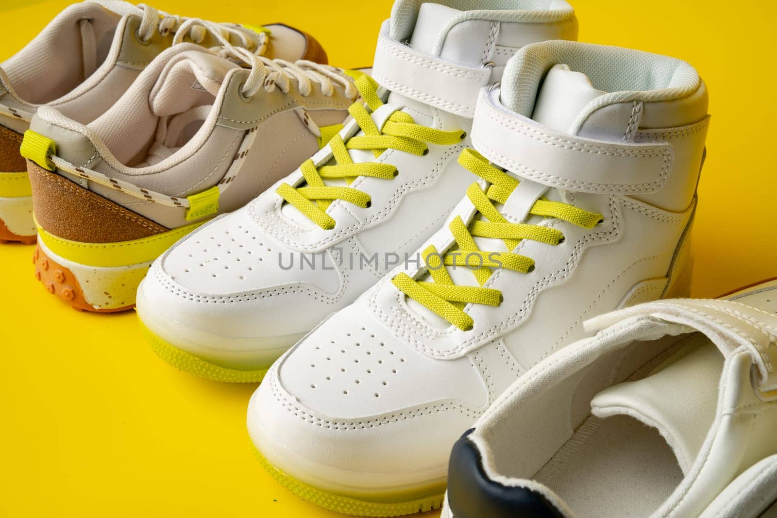 Several pairs of fashion trendy sport shoes on yellow background close up