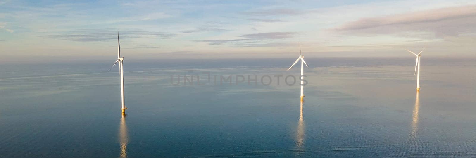 Beautiful sunset above the windmills on the field in the ocean during sunset