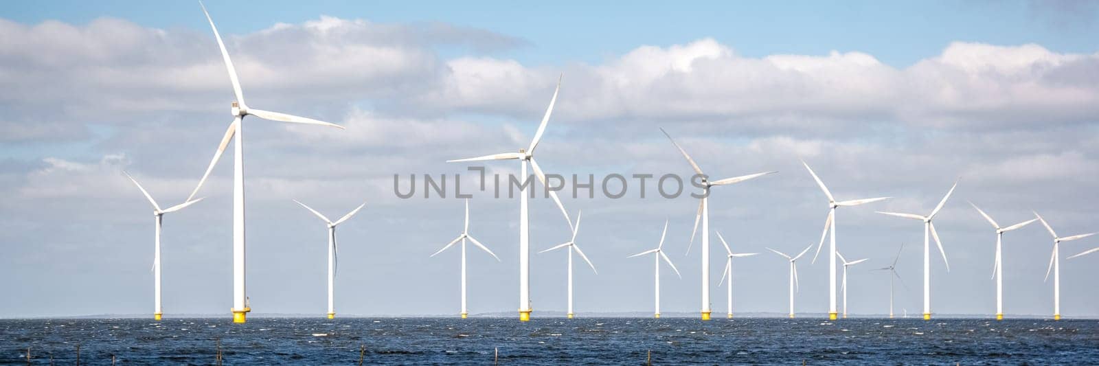 offshore windmill park with clouds and a blue sky, wind mill turbines in the Netherlands by fokkebok