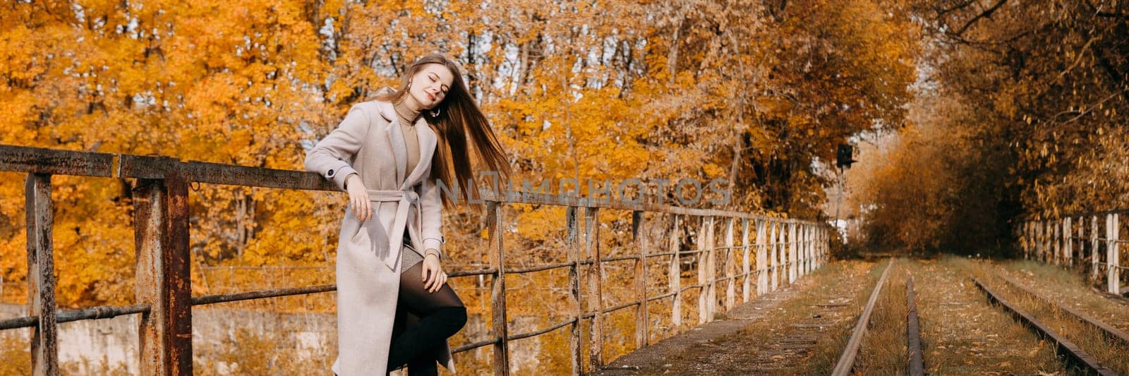 beautiful long-haired woman walks through the autumn streets. Railway, autumn, woman in a coat. by Annu1tochka