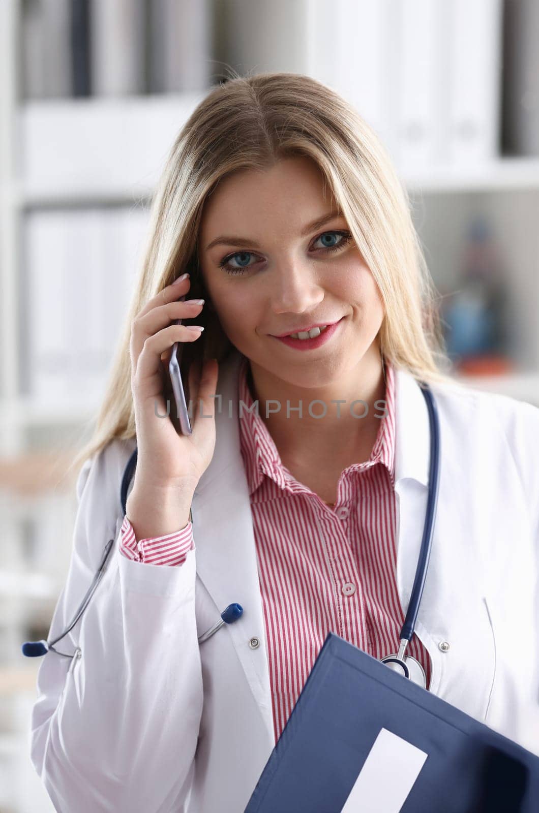 Beautiful female blond doctor talking on phone by kuprevich