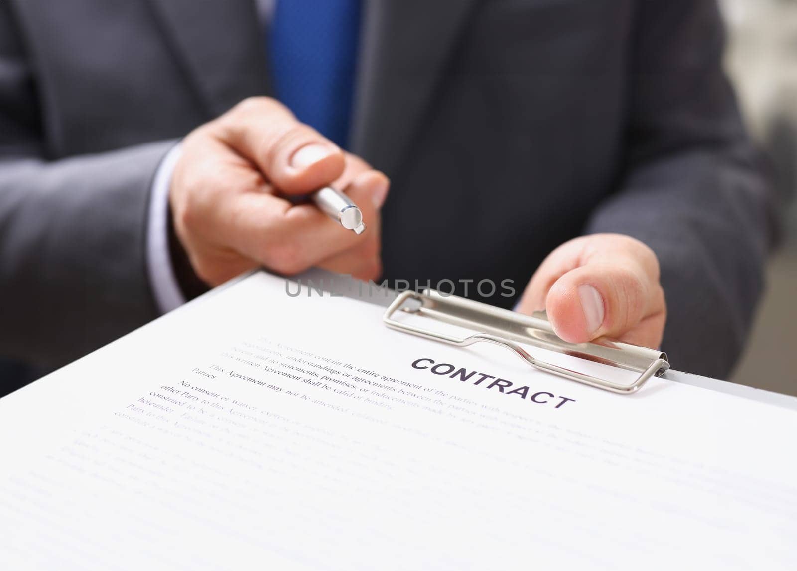 Male arm in suit offer contract form on clipboard pad and silver pen to sign closeup. Strike a bargain for profit, white collar motivation union decision corporate sale insurance agent concept