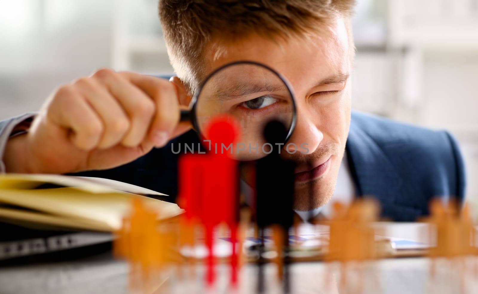 Man in suit look thru loupe on statuettes closeup by kuprevich