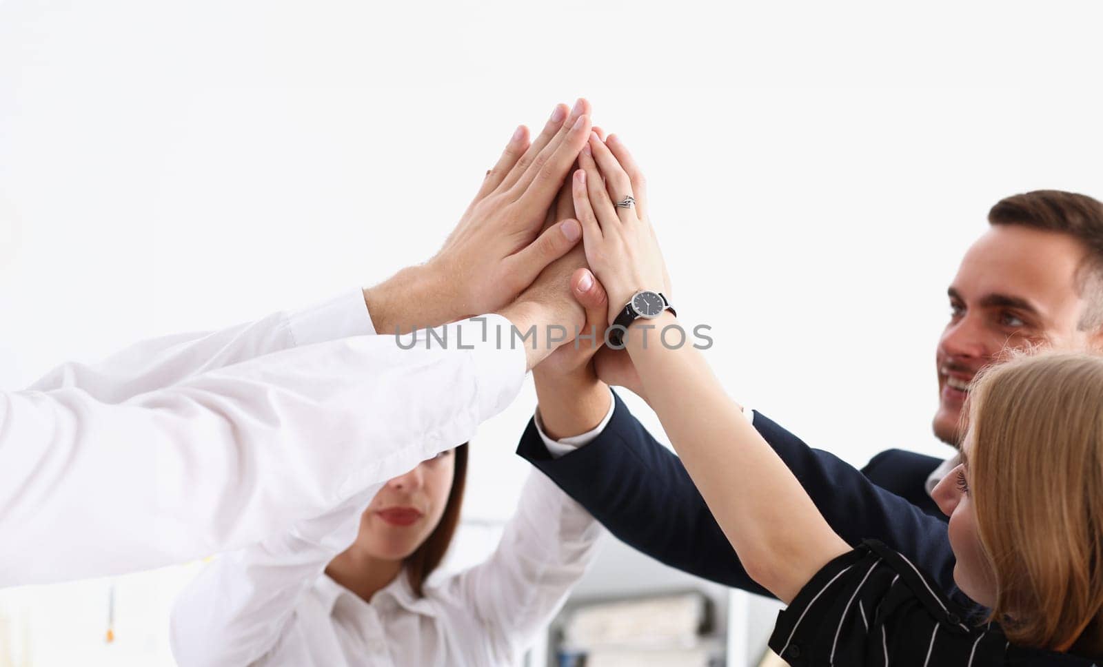 Group of people in suits crossed hands in pile for win closeup. White collar leadership high five cooperation initiative achievement corporate life style friendship deal heap stack concept