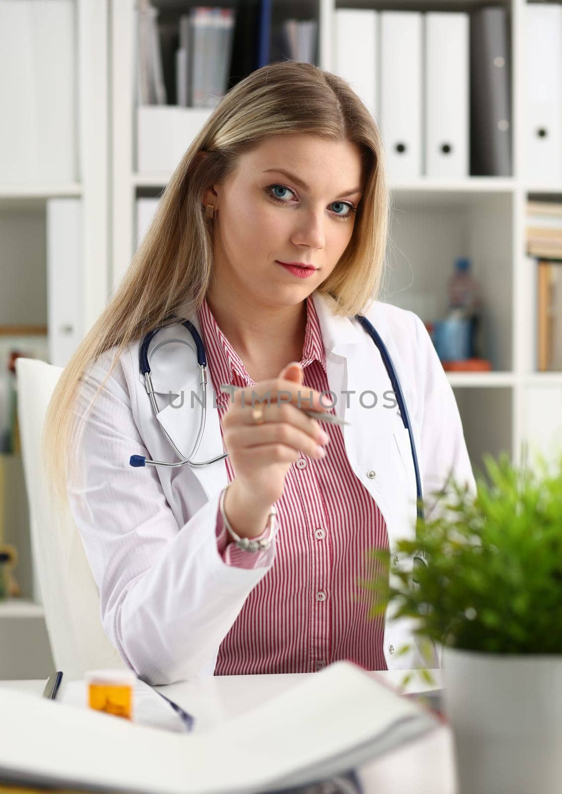 Beautiful smiling female doctor sit at workplace by kuprevich