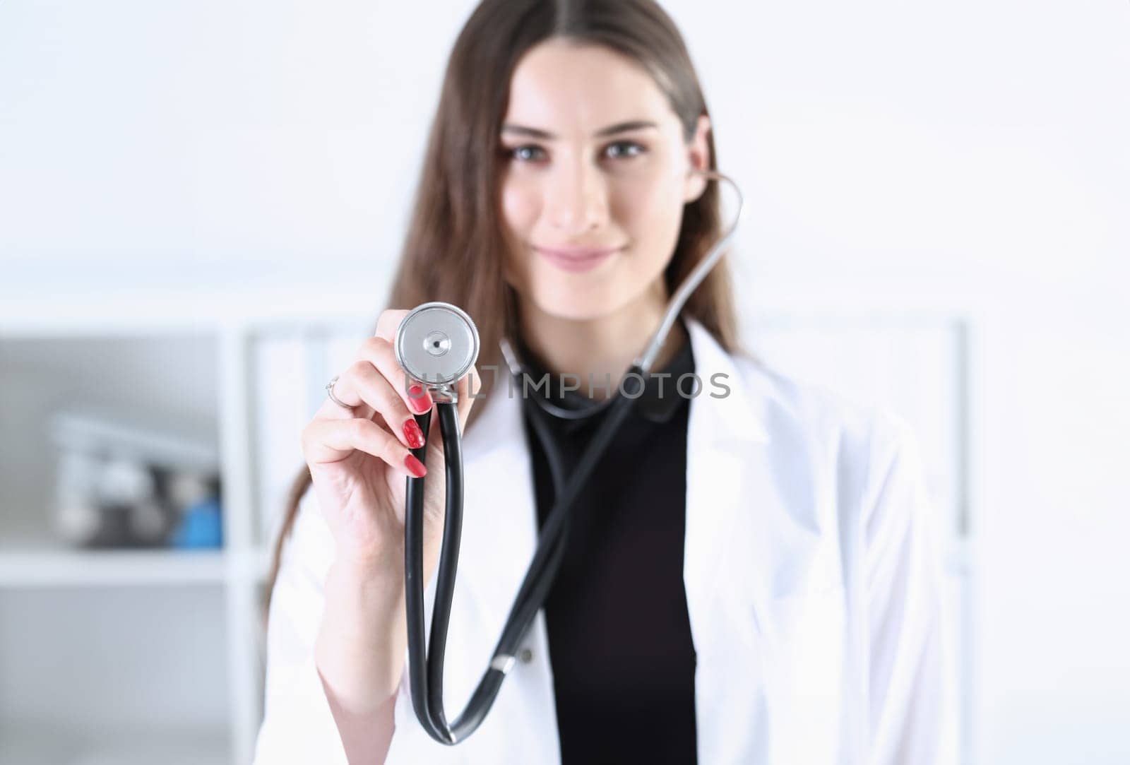 Beautiful smiling female doctor hold in hand stethoscope head going to listen patient. Medic shop or store physical disease prevention er consultant 911 pulse measure healthy lifestyle concept