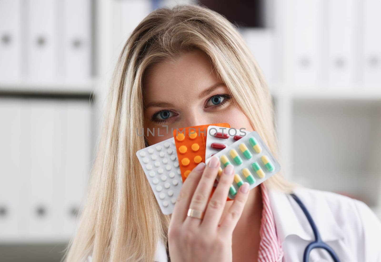 Female doctor hand holding pack of different tablet blisters at workplace closeup. Panacea life save service prescribe medicament legal drug store disease healing blood pressure concept