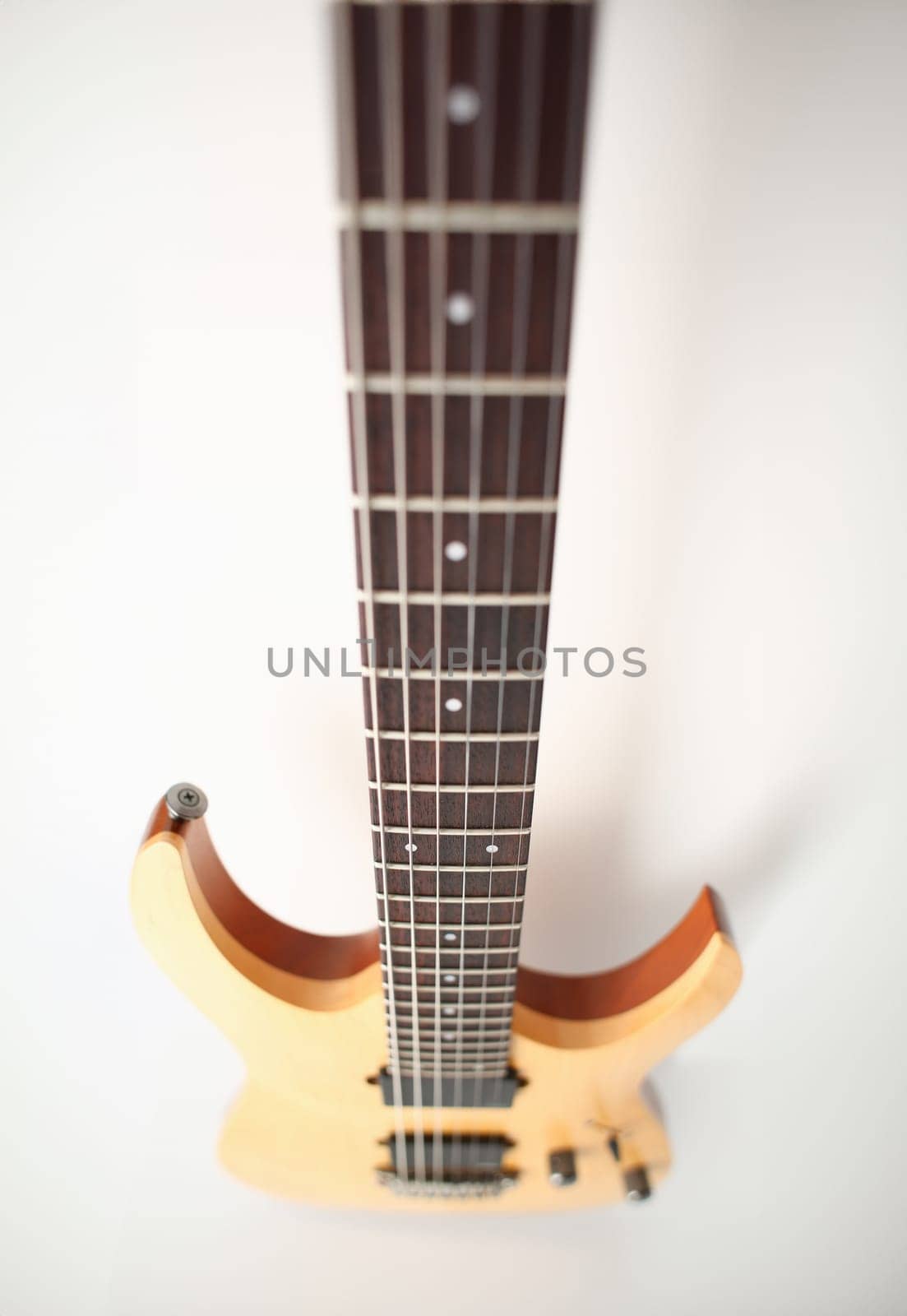 Classic shape wooden electric guitar with rosewood neck closeup. Six stringed learning lesson musician school education art leisure electrical vintage stage wood guitar concept