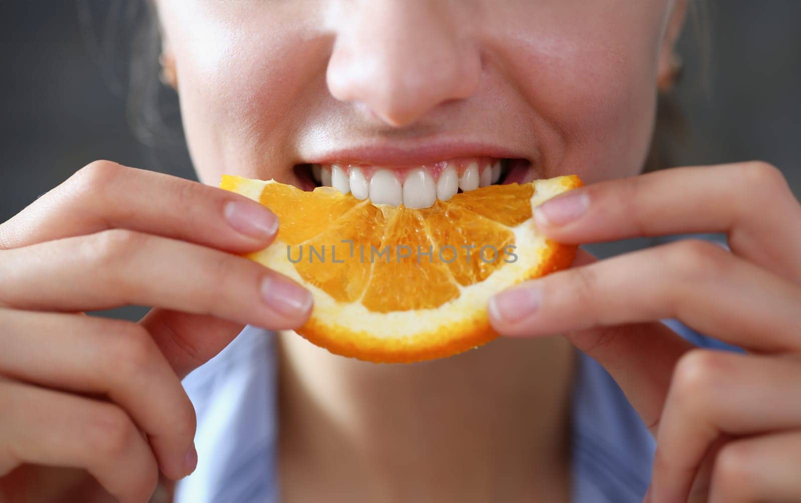 Beautiful brunette smiling woman eat sliced raw tasty orange half at kitchen in the morning closeup. Weight loss beauty fit concept