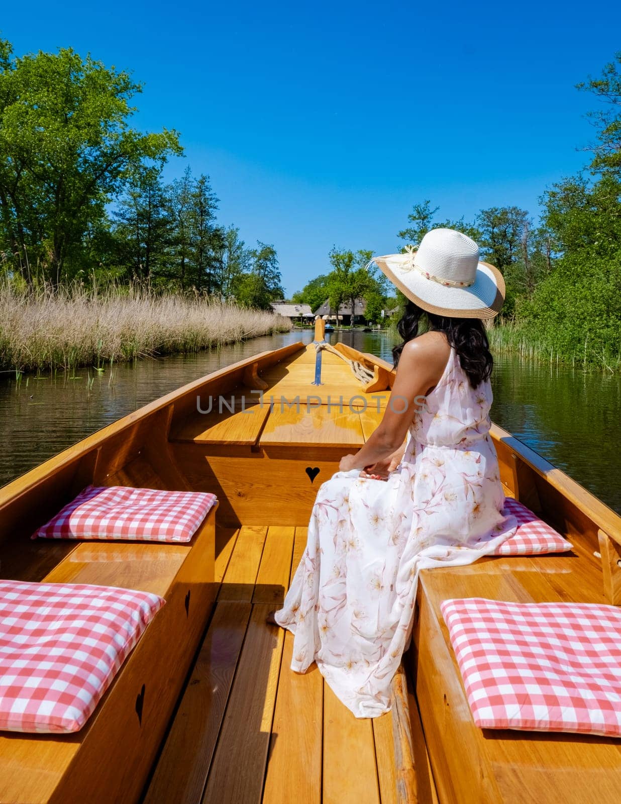 Asian women visit Giethoorn Netherlands, Asian female visit the village with a boat, view of the famous village with canals and rustic thatched roof houses in the Netherlands alongside the canals