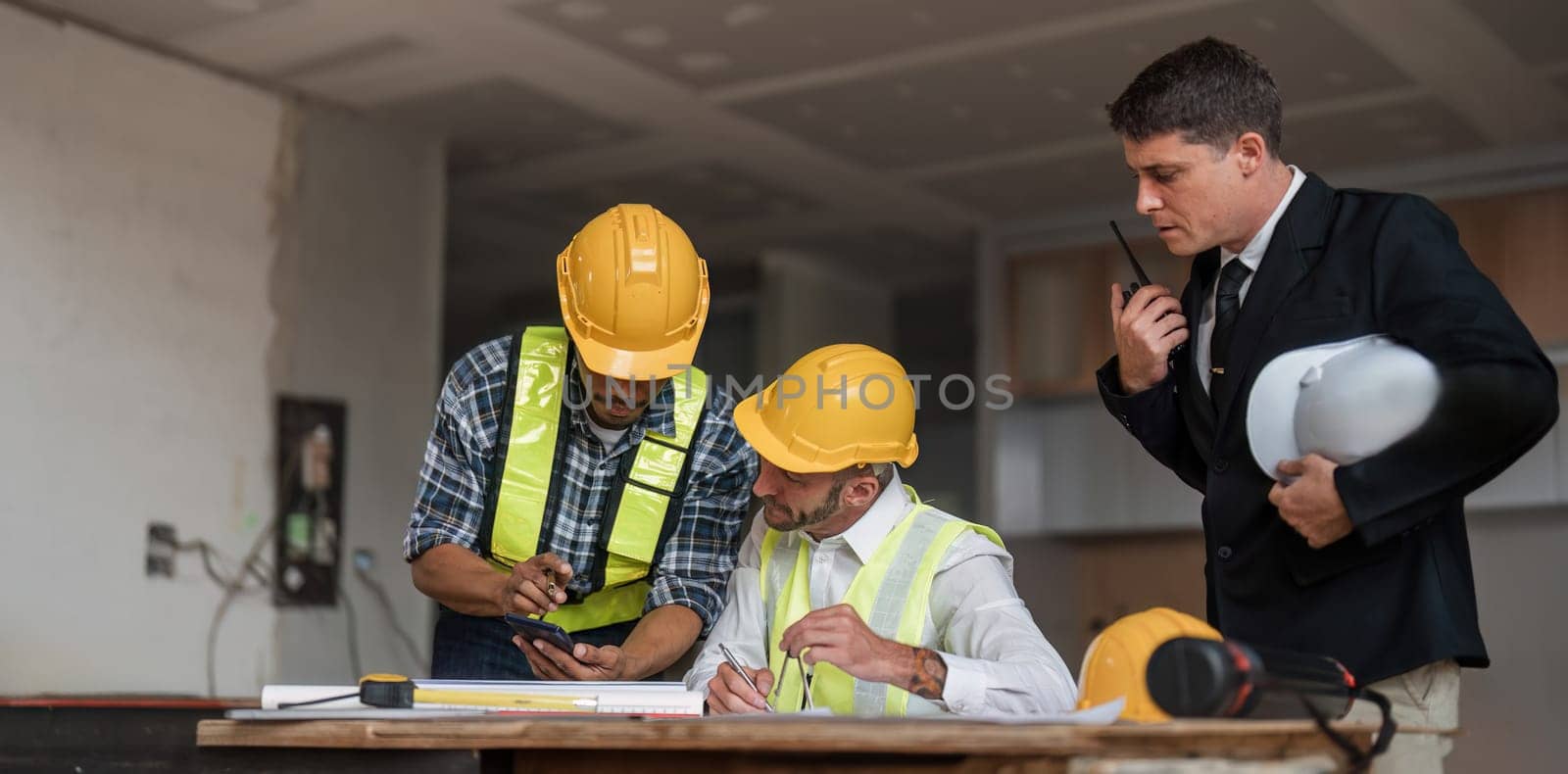 Diverse Team of Specialists Use Laptop on Construction Site. Real Estate Building Project with Engineer Investor and Businessman Checking Area, working on Civil Engineering, Discussing Strategy Plan by wichayada
