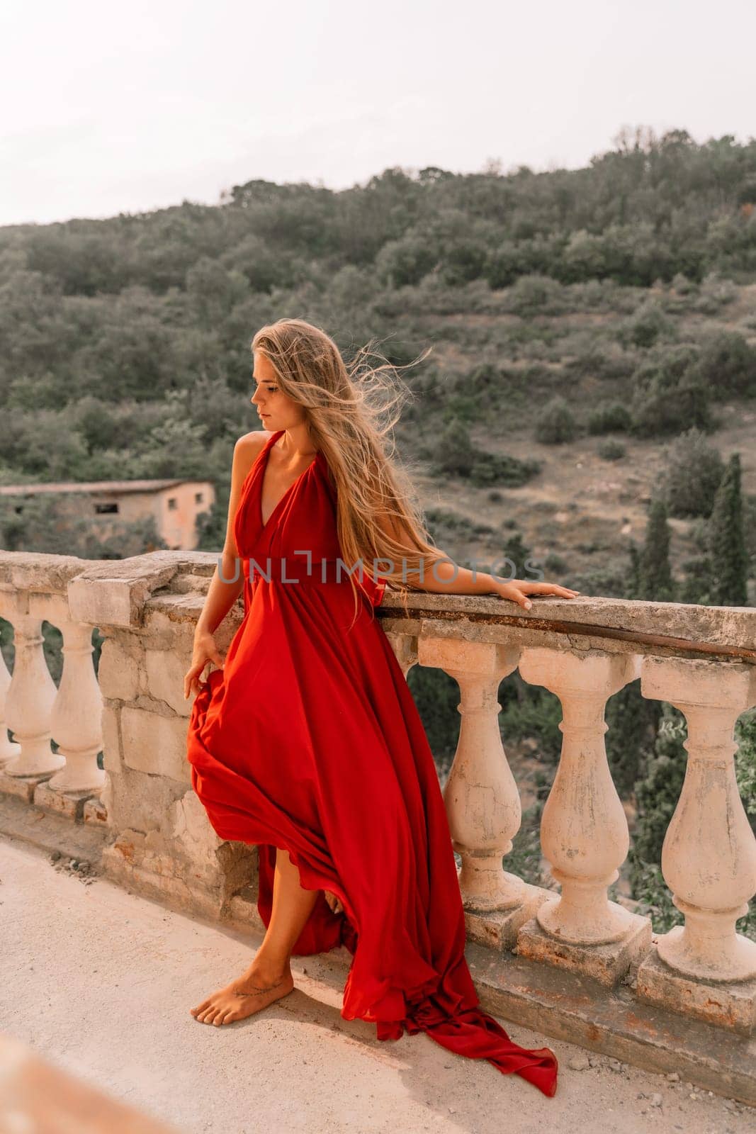 Woman red dress. Summer lifestyle of a happy woman posing near a fence with balusters over the sea