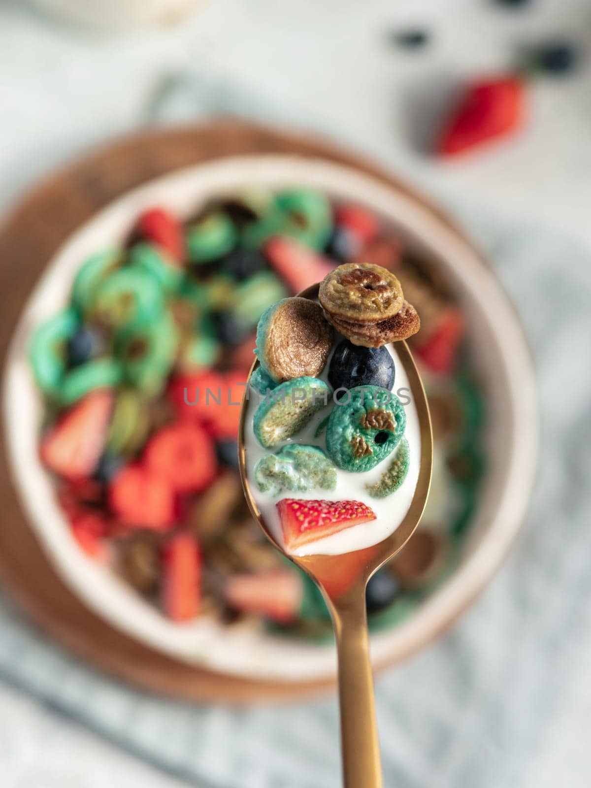 Trendy food - pancake cereal. Bowl of colorful mini cereal pancakes in spoon with milk. Tiny pancakes with natural color - green matcha, turquose spirulina, blue pea, red fragon fruit. Copy space