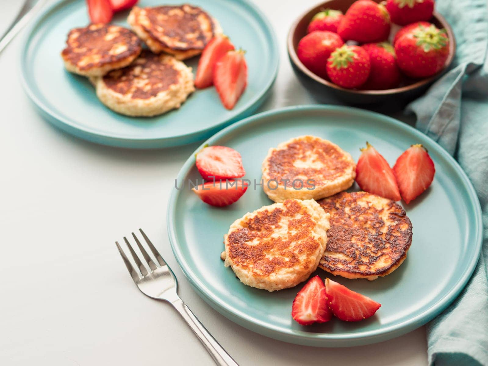 Sweet cheese pancakes on plate served strawberries. Cottage cheese pancakes, syrniki, ricotta fritters, curd fritters, Copy space for text or design.