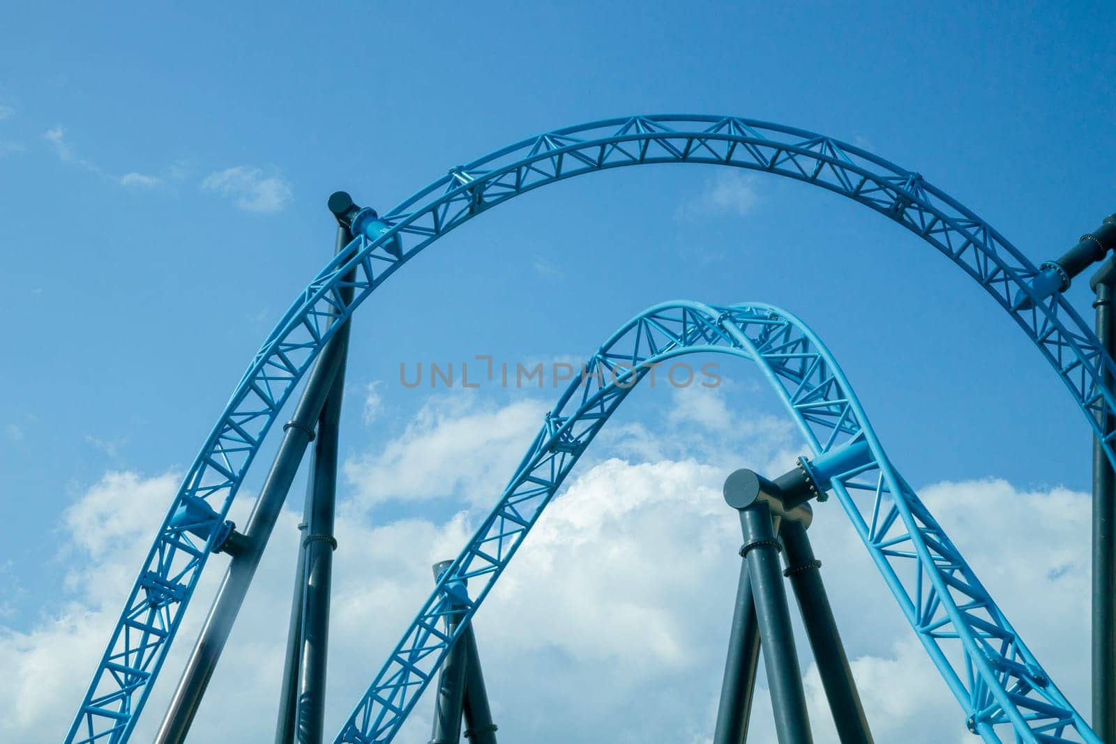 Helsinki, Finland - 19 AUGUST 2024: Linnanmaki amusement park with roller coaster Taiga in motion, blue sky on a background, happy people