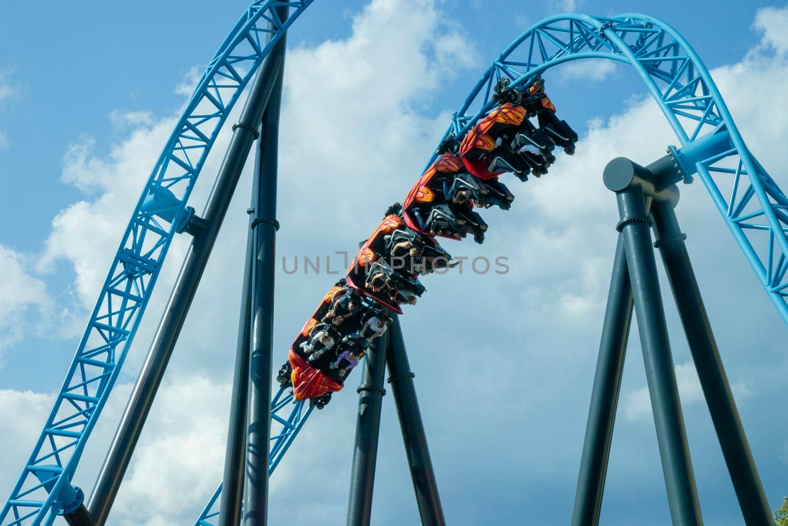 Helsinki, Finland - 19 AUGUST 2024: Linnanmaki amusement park with roller coaster Taiga in motion, blue sky on a background, happy people