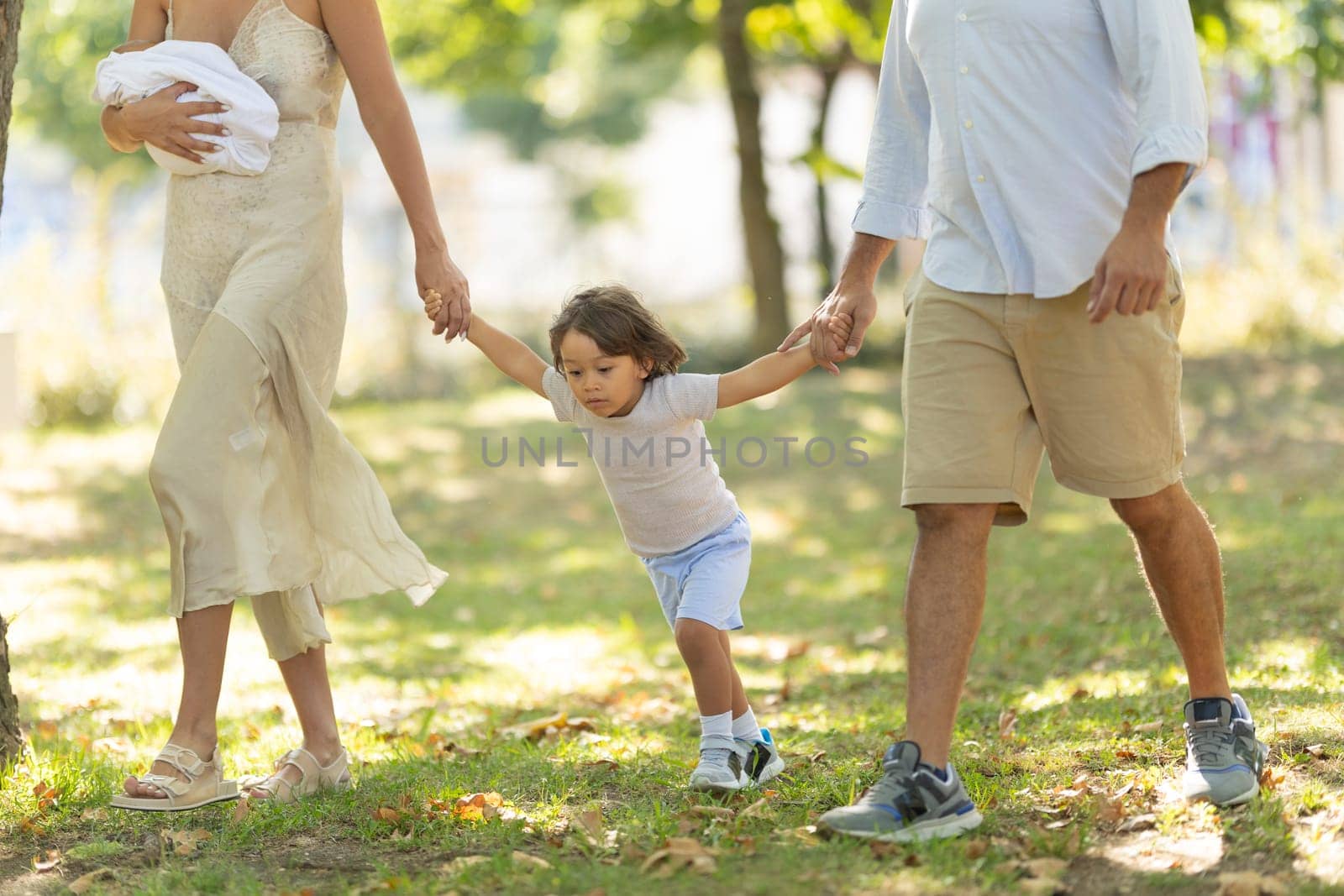 Young family is enjoying a sunny day walking together in a park