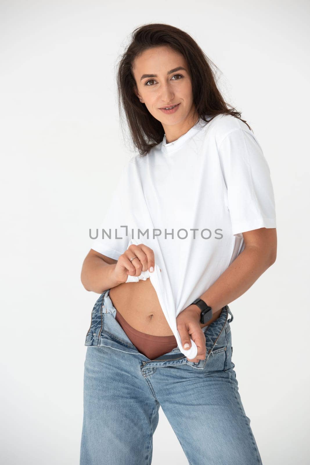 Happy beautiful girl posing in a new hot summer look. Wearing blue jeans and white waistcoat.