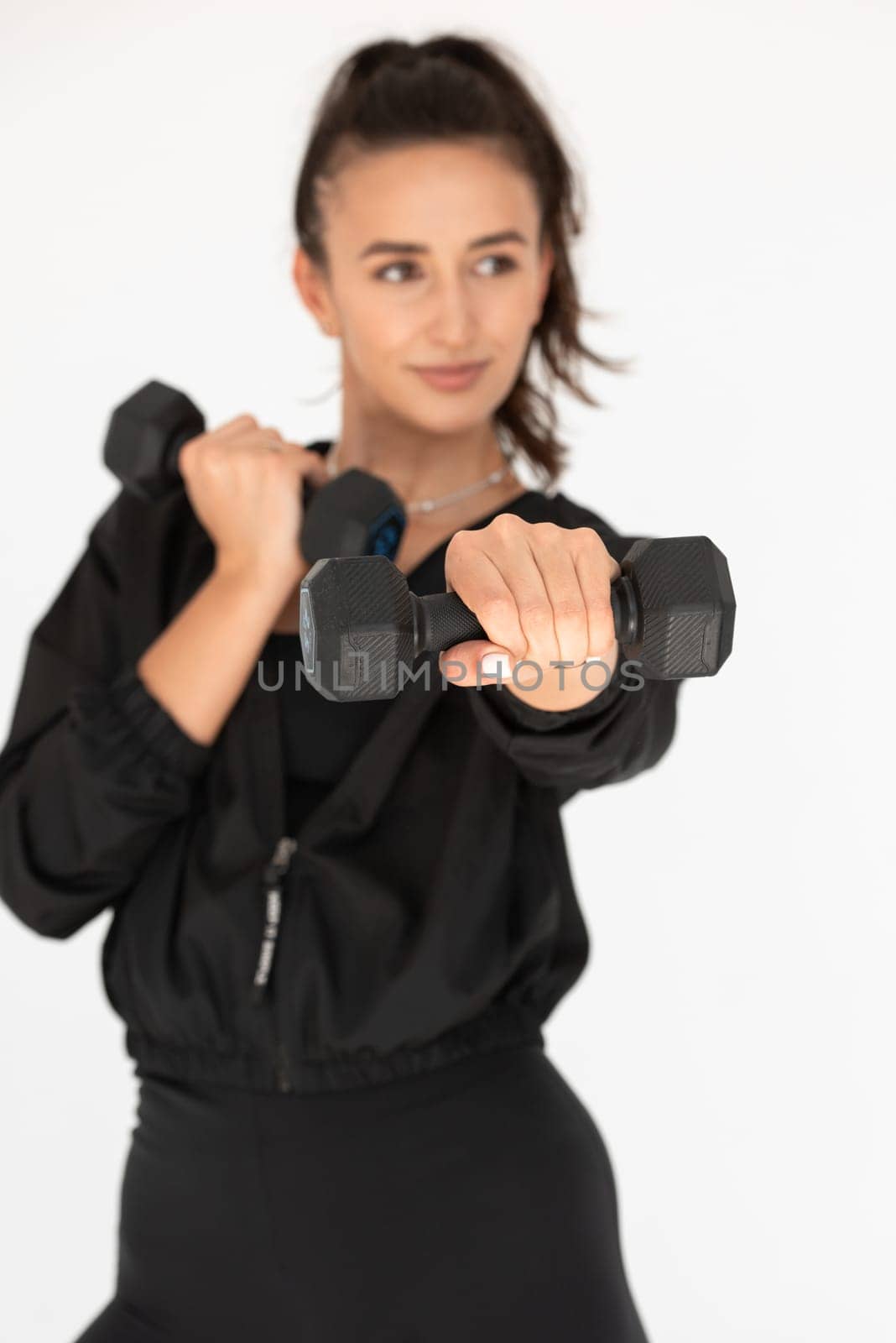 Young girl posing with dumbbells for power training, indoors. athlete wearing black leggings and shirt.