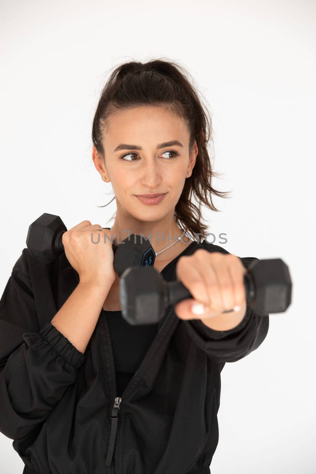 Young girl posing with dumbbells for power training, indoors. athlete wearing black leggings and shirt.