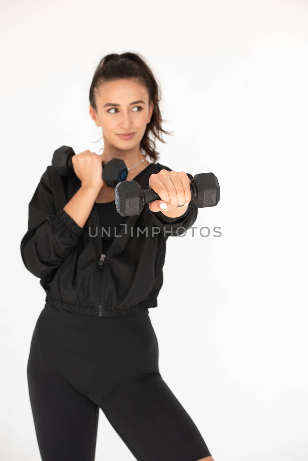 Young girl posing with dumbbells for power training, indoors. athlete wearing black leggings and shirt.