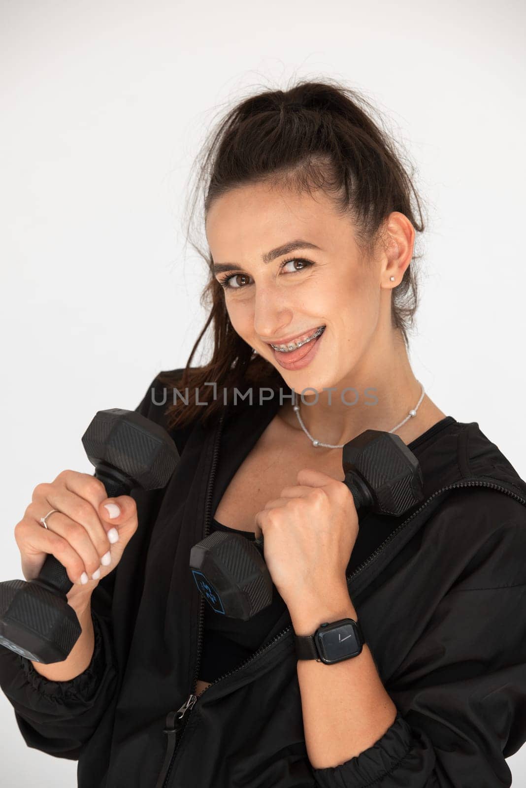 Young girl posing with dumbbells for power training, indoors. athlete wearing black leggings and shirt.