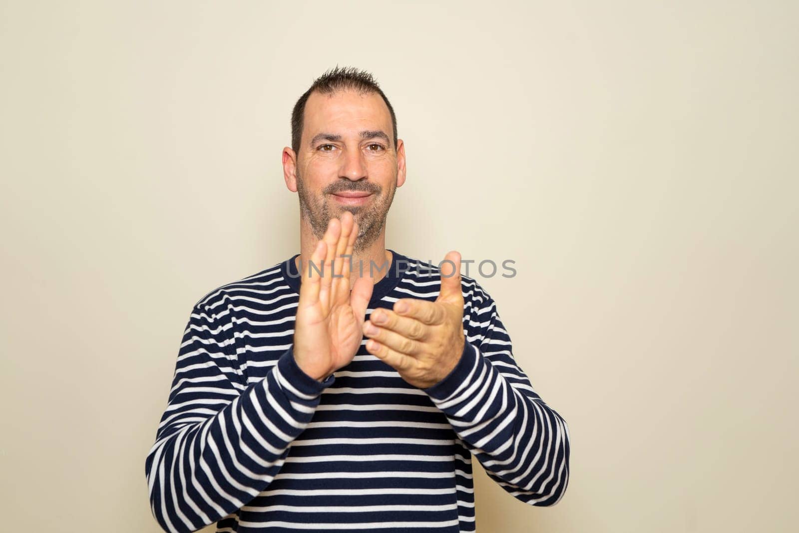 Bearded hispanic man about 40 years old isolated over beige background applauding after his presentation at a conference.