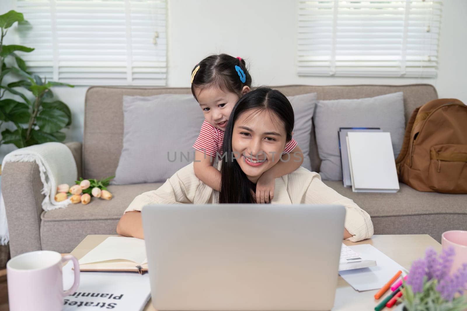 A loving mother and her child share a warm moment as they engage with a laptop at home, combining family time with digital learning.