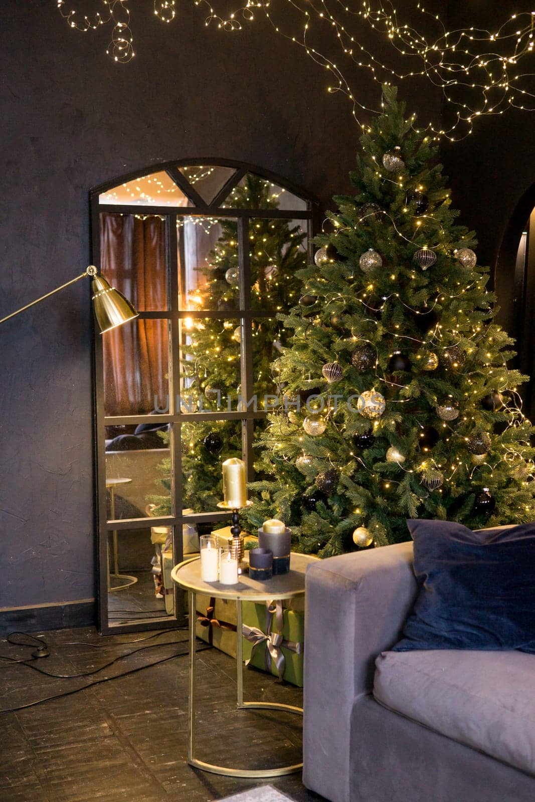Christmas interior with a beautiful Christmas tree, sofa, light bulbs and dark background