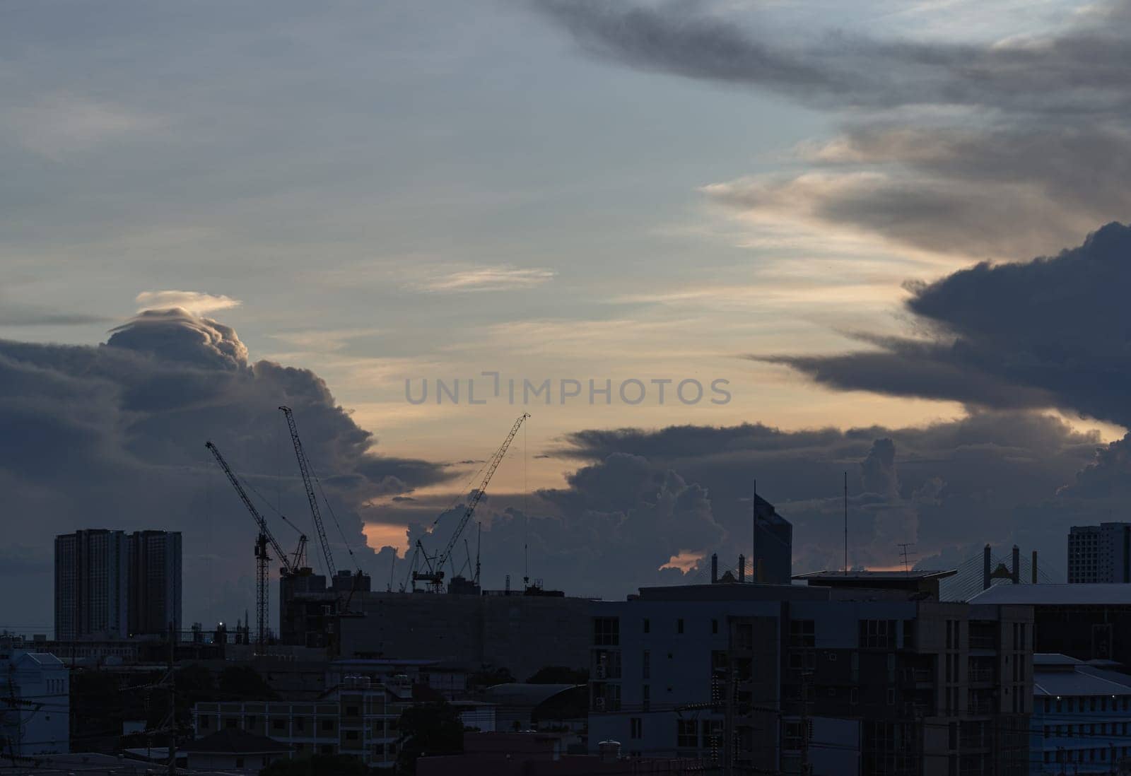 Bangkok, Thailand - Aug 22, 2024 - Silhouette view of Construction of tall buildings with a crane and background of Dramatic sky in the city of Bangkok. Tower crane, Construction cranes, Construction and urban development. use it as your Wallpaper, Poster and Space for text, Selective focus.