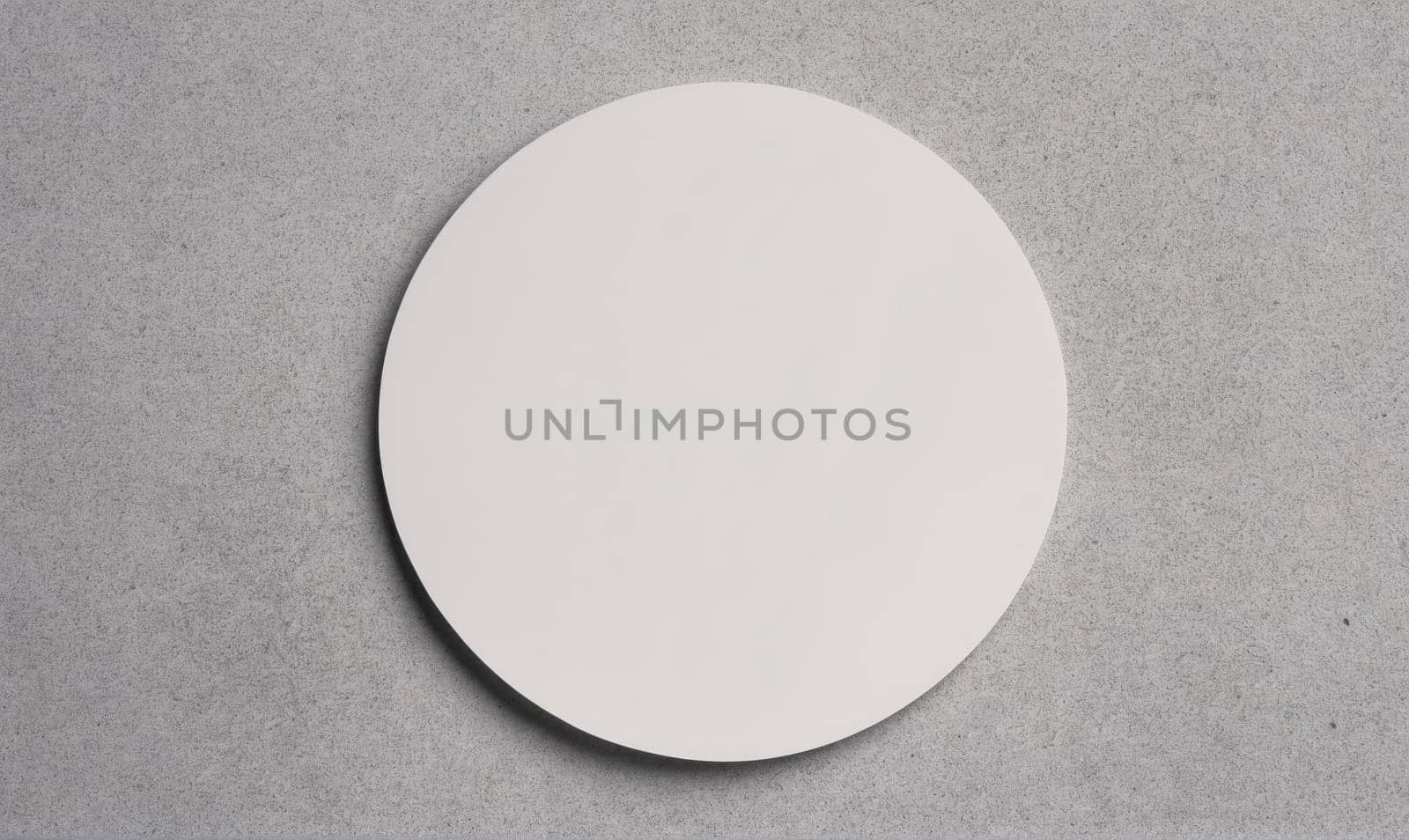 A white round plate sits on a gray concrete surface.