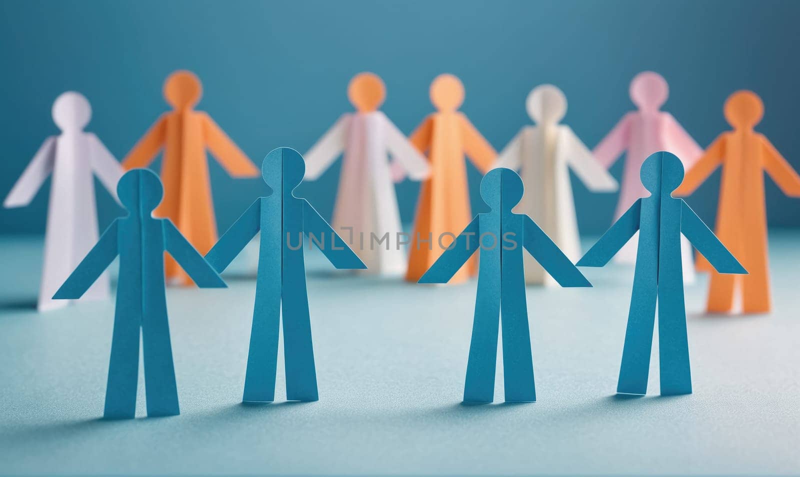 A group of paper figures of various colors stand in a circle, some holding hands. The figures are arranged in a way that suggests a sense of togetherness and unity