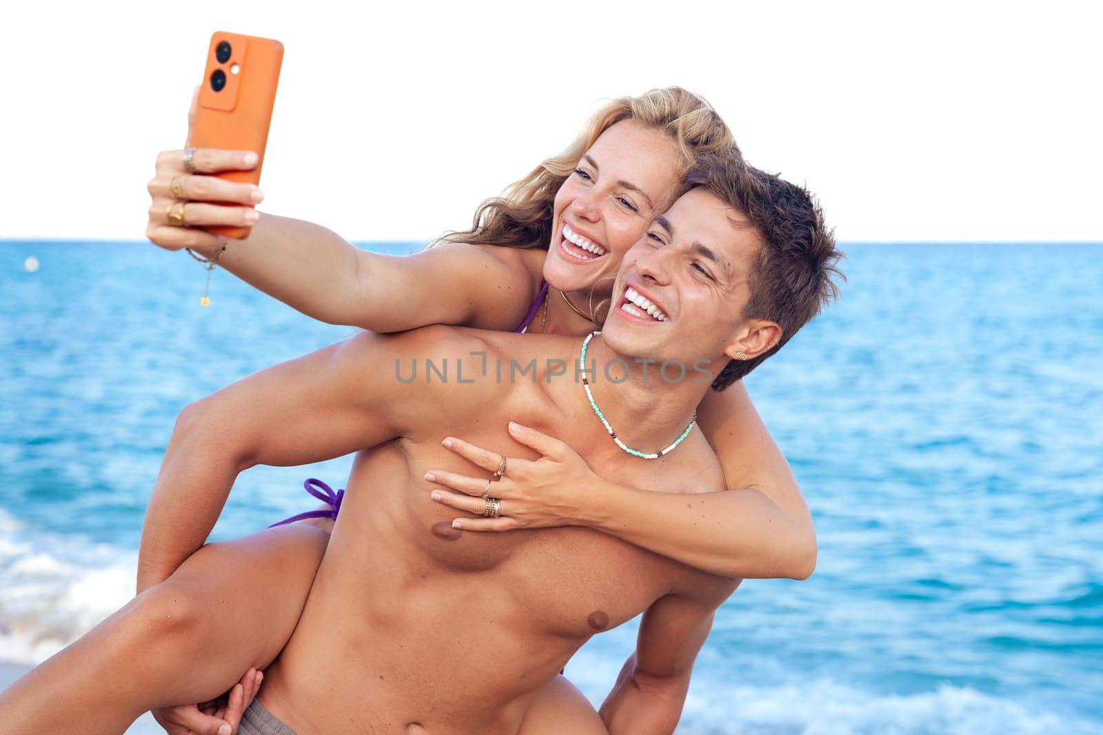Smiling young woman and man enjoying vacation. Beautiful and cheerfulcoupleof generation z pose for a photo with a mobile phone.