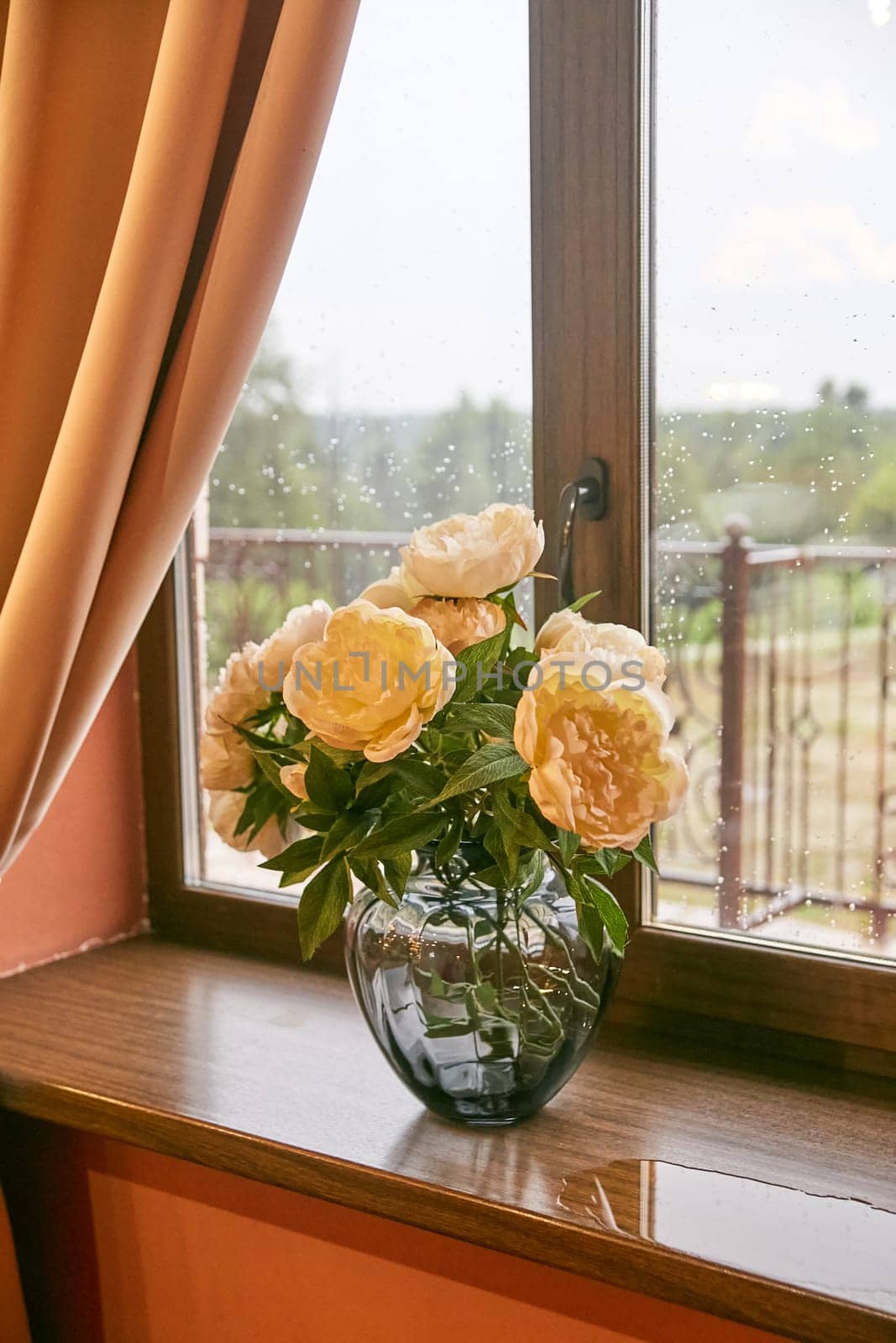 Cream peonies in a glass vase on the window. Flowers at home. Cosiness.
